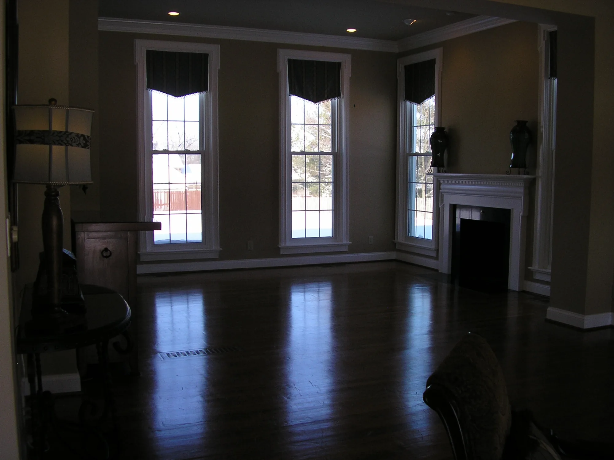 A room with hardwood floors and tall draped windows