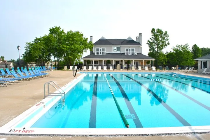 The Waterford neighborhood swimming pool on a sunny day, surrounded by lounge chairs and shade umbrellas