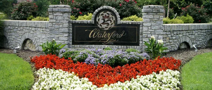 A Waterford pond with a fountain at the neighborhood's main entrance, with waterfowl on the bank and homes beyond